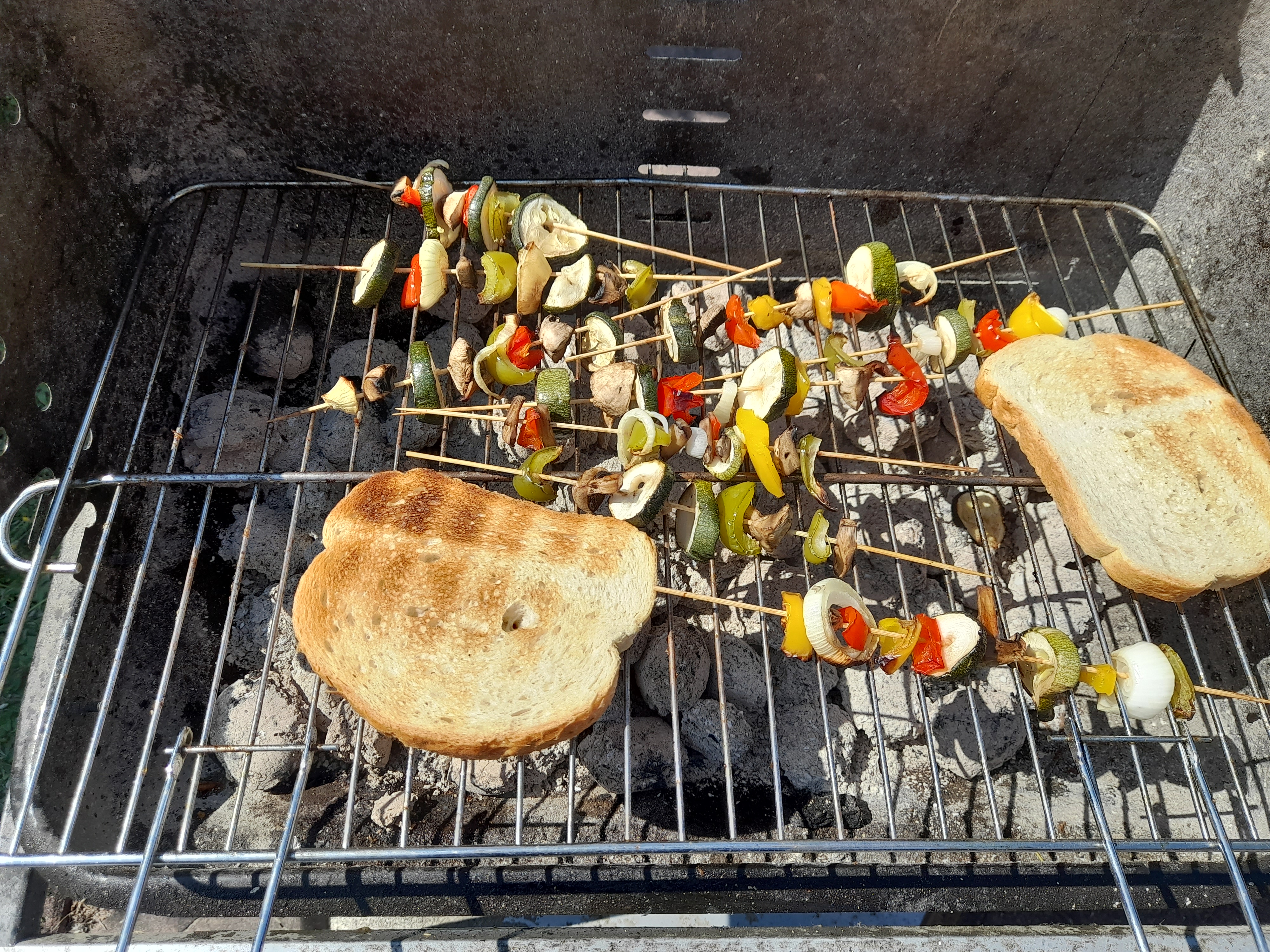 Upieczone szaszłyki warzywno mięsne i kromki chleba na ruszcie grillowym